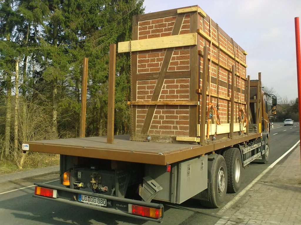 Lastwagen transportiert große stapelbare Holzstruktur auf Straße